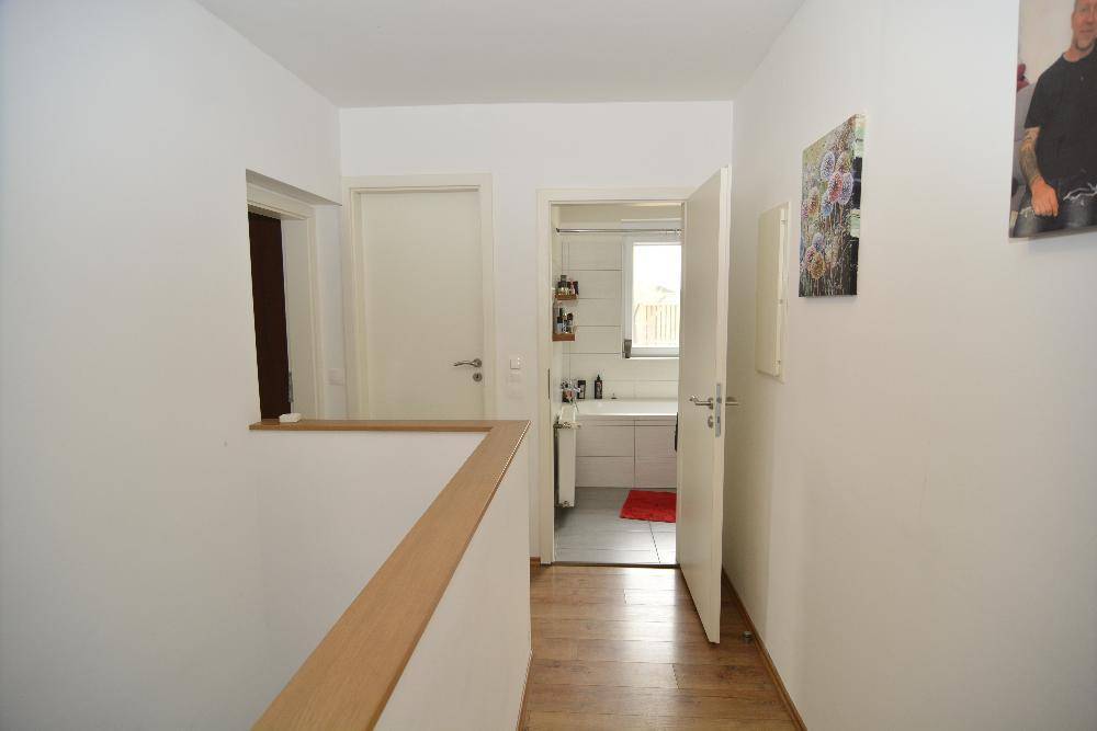 Heller Flur mit Holzgeländer und Zugang zu weiteren Räumen und dem Badezimmer.