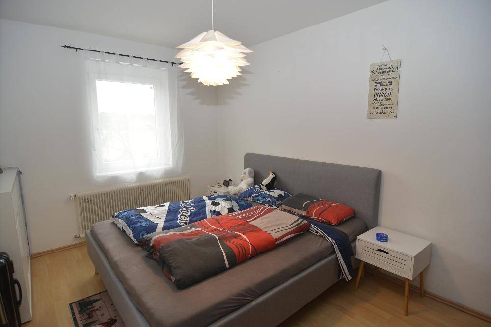 Schlafzimmer mit Doppelbett, Holzfußboden und Fenster für natürliches Licht.