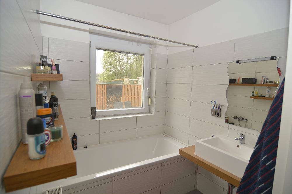 Modernes Badezimmer mit Badewanne, Waschbecken und Fenster für Tageslicht.