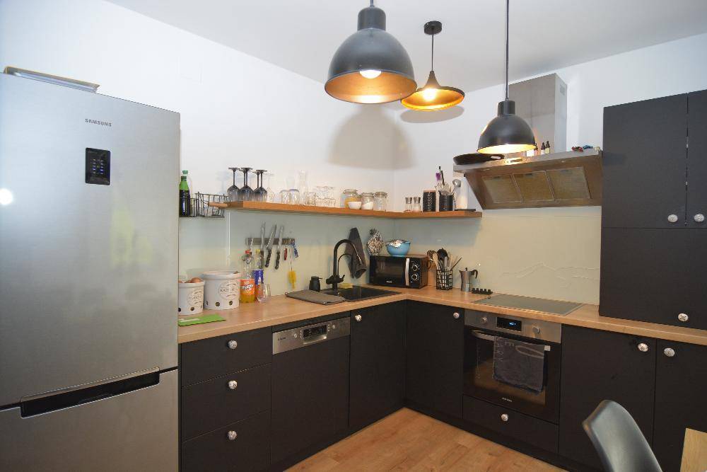 Moderne Küche mit dunklen Schränken, Holztheke und Edelstahlgeräten.