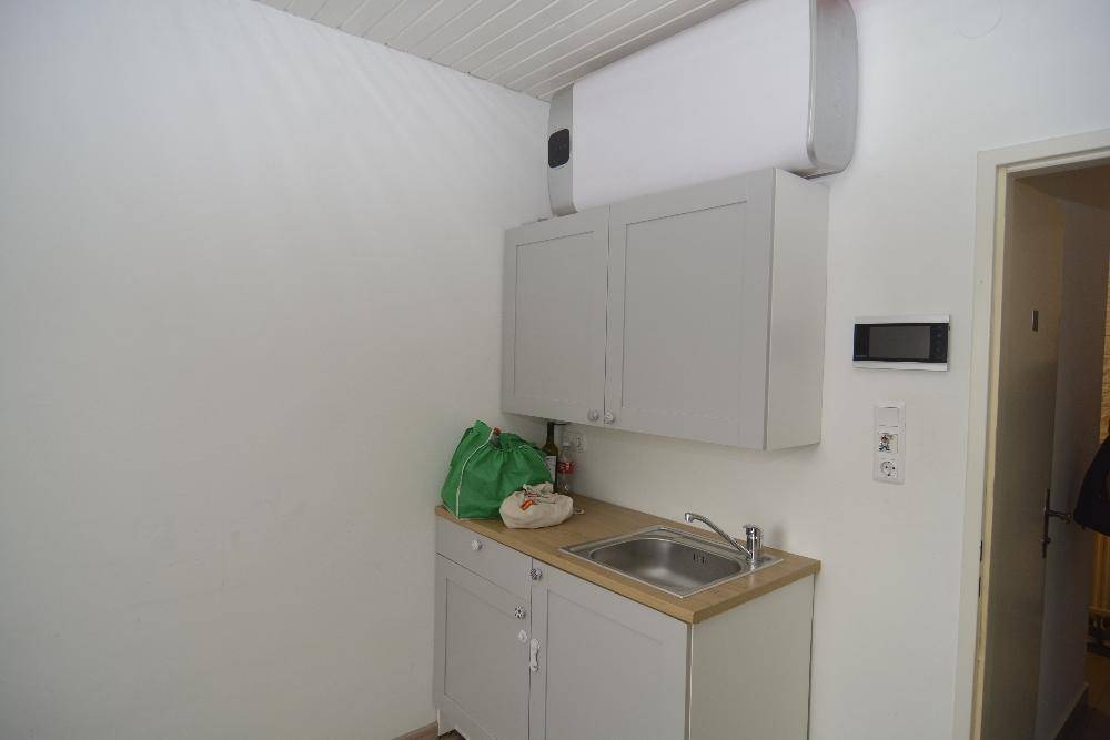Kleiner Hauswirtschaftsraum mit Spülbecken, Hängeschränken und Warmwasserboiler.
