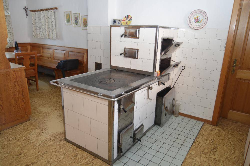 Traditionelle Küche mit einem großen, gefliesten Holzofen und einer gemütlichen Sitzecke.