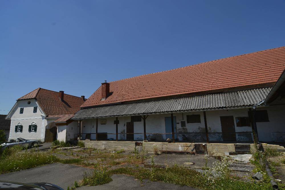 Ansicht des Haupthauses und eines langen Nebengebäudes mit rotem Ziegeldach und Veranda.