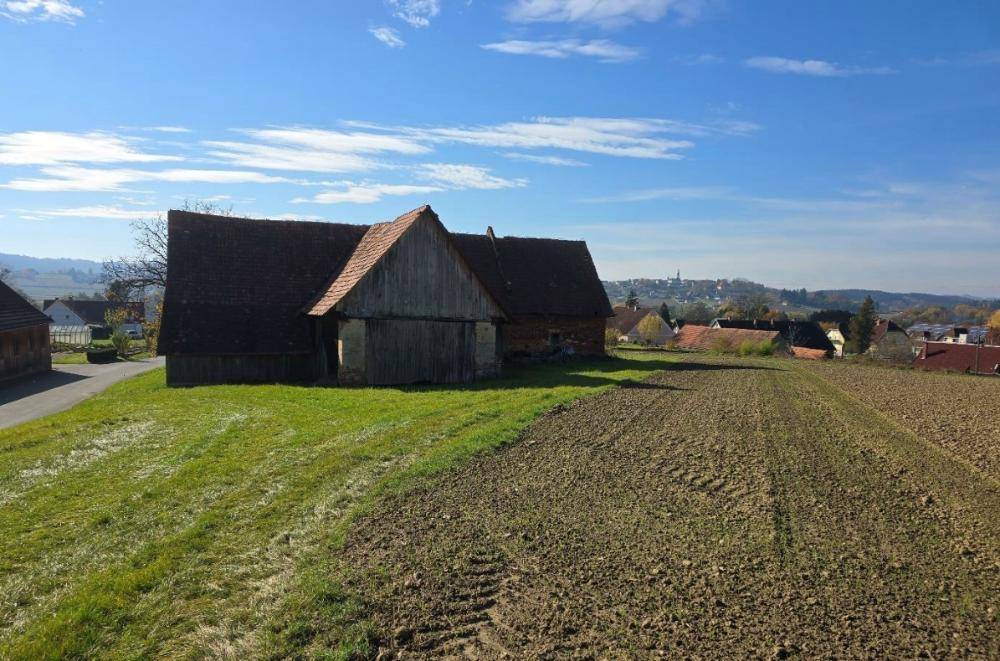 Altes Scheunengebäude mit Ziegeldach und weitem Blick über Felder und ländliche Umgebung.