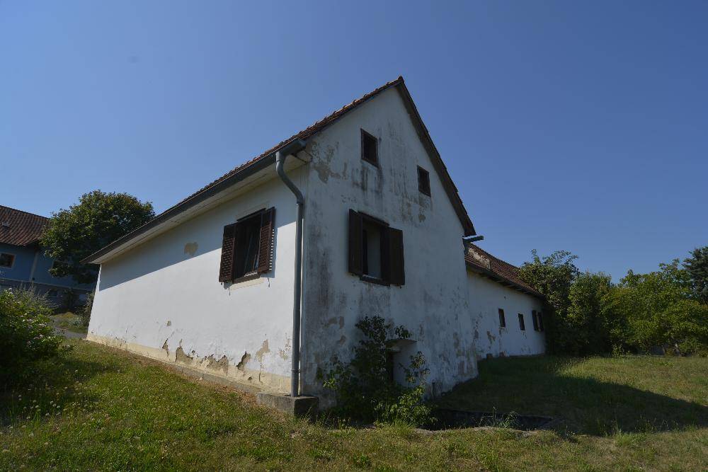 Seitenansicht des traditionellen Hauses mit weißer Fassade und sichtbaren Abnutzungserscheinungen.