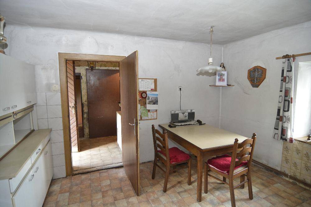 Essbereich in der Küche mit Holztisch und Stühlen, angrenzend an einen weiteren Raum.