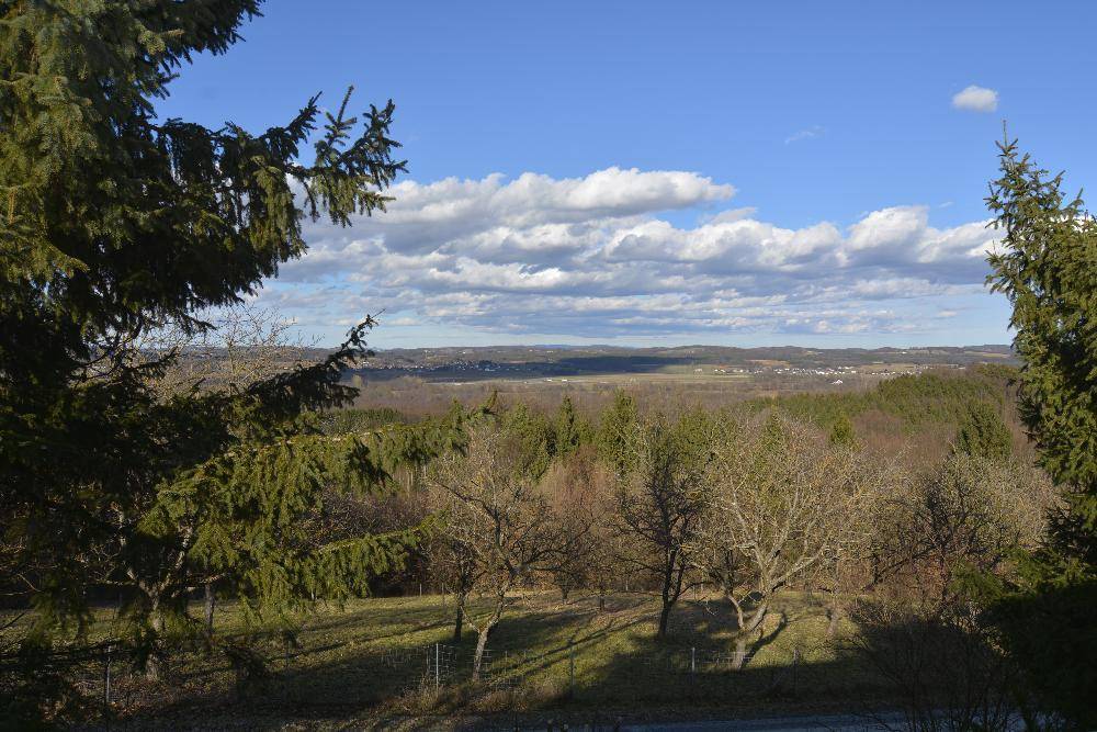 Weitläufiger Panoramablick über ein Tal und bewaldete Hügel unter einem strahlend blauen Himmel.