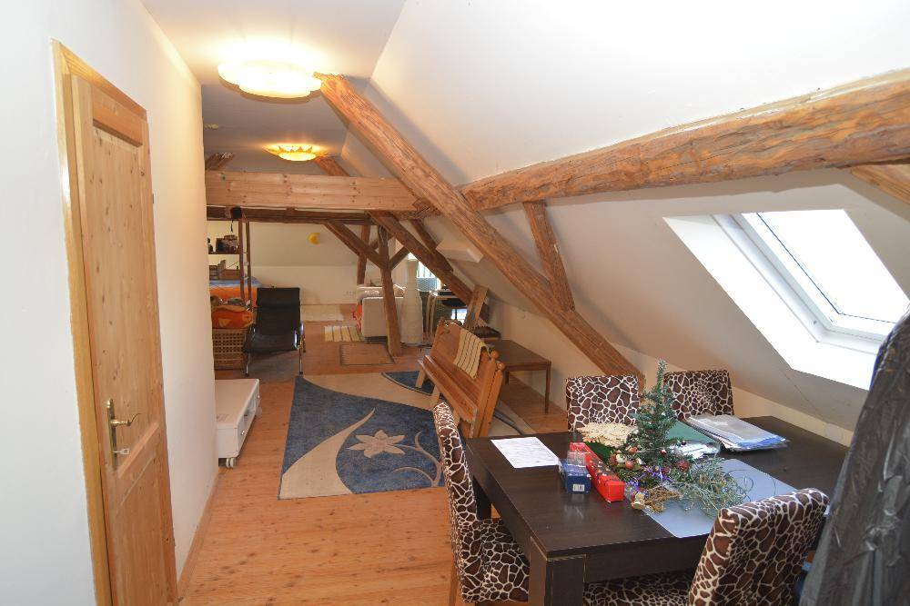 Essbereich im Dachgeschoss mit Holzbalken, Dachfenster und Holzboden.