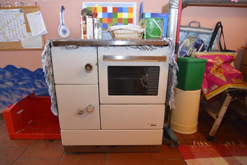 Rustikaler alter Ofen mit Backfach in einer einfachen Küchenecke.