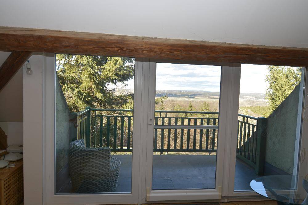 Balkon mit weitem Blick über die grüne Landschaft und Sitzgelegenheiten.