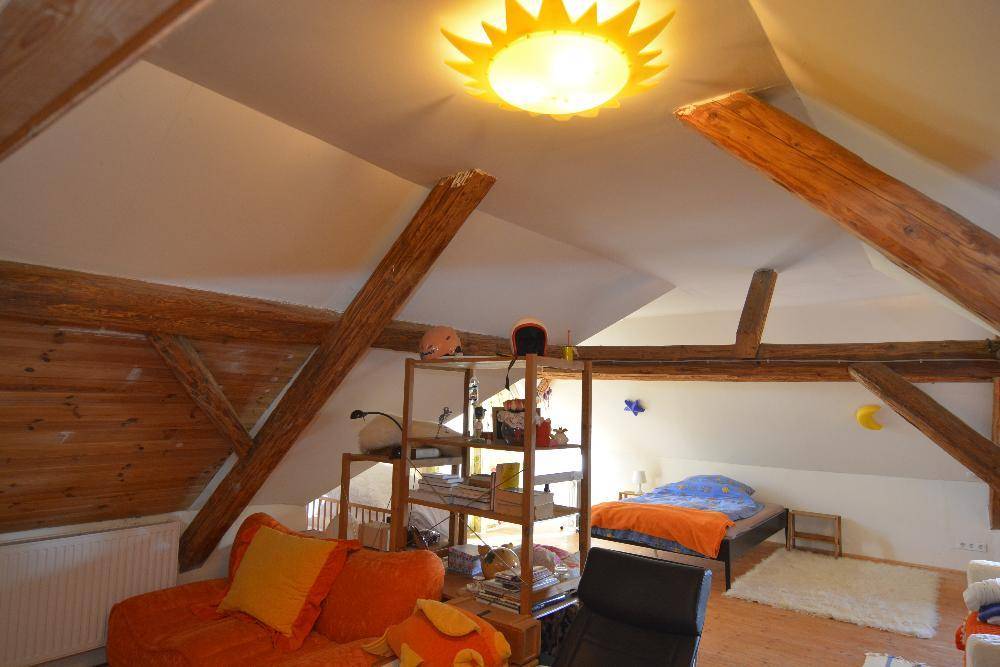 Gemütliches Schlafzimmer im Dachgeschoss mit Holzbalken und schrägen Wänden.