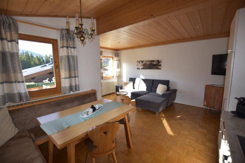 Gemütlicher Wohn-Essbereich mit Holzbalkendecke, Parkettboden und traditioneller Sitzecke mit Bergblick.