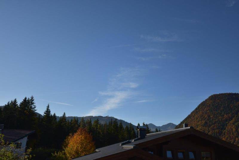 Panoramablick auf die umliegenden Berge und den blauen Himmel über einem Hausdach.