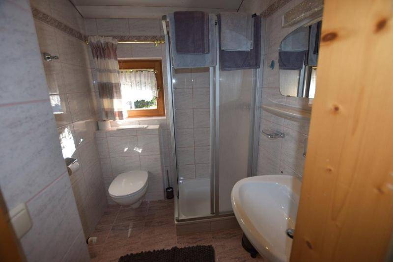 Funktionales Badezimmer mit Fliesen, Duschkabine, WC, Waschbecken und Fenster für Tageslicht.