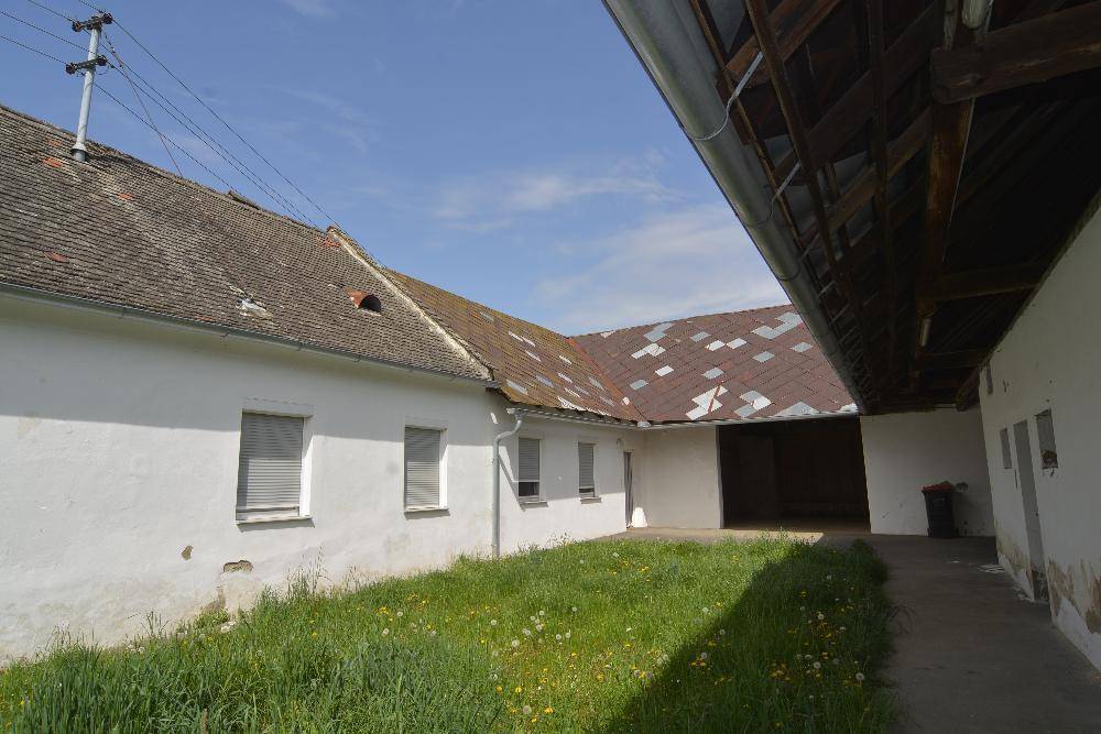 Ländlicher Gebäudekomplex mit weiß getünchten Wänden und offenem Innenhof.