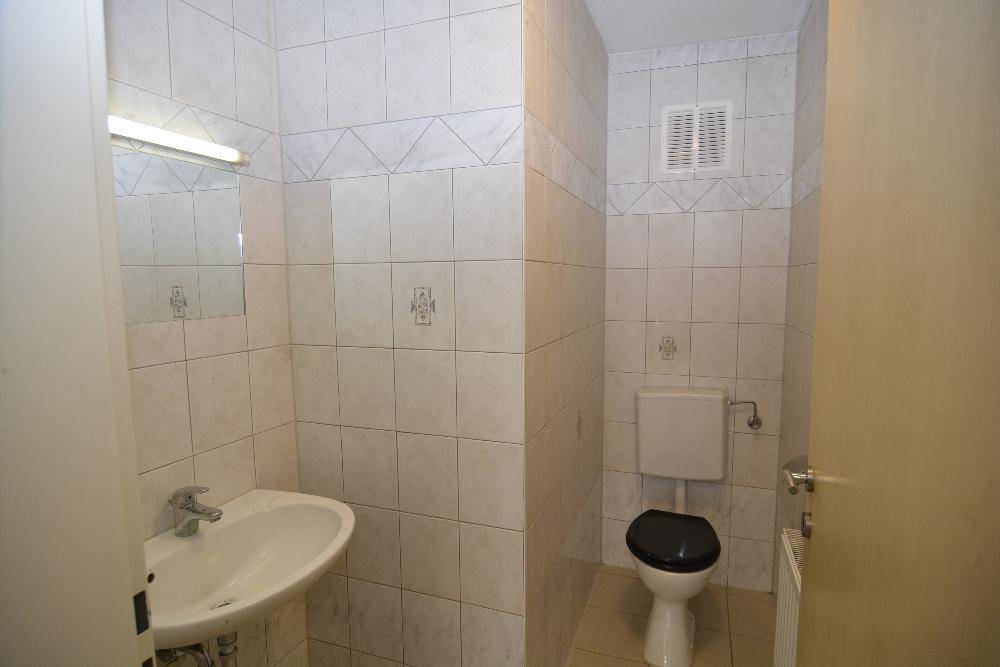 Gefliestes Gäste-WC mit Waschbecken, Toilette und Spiegel.