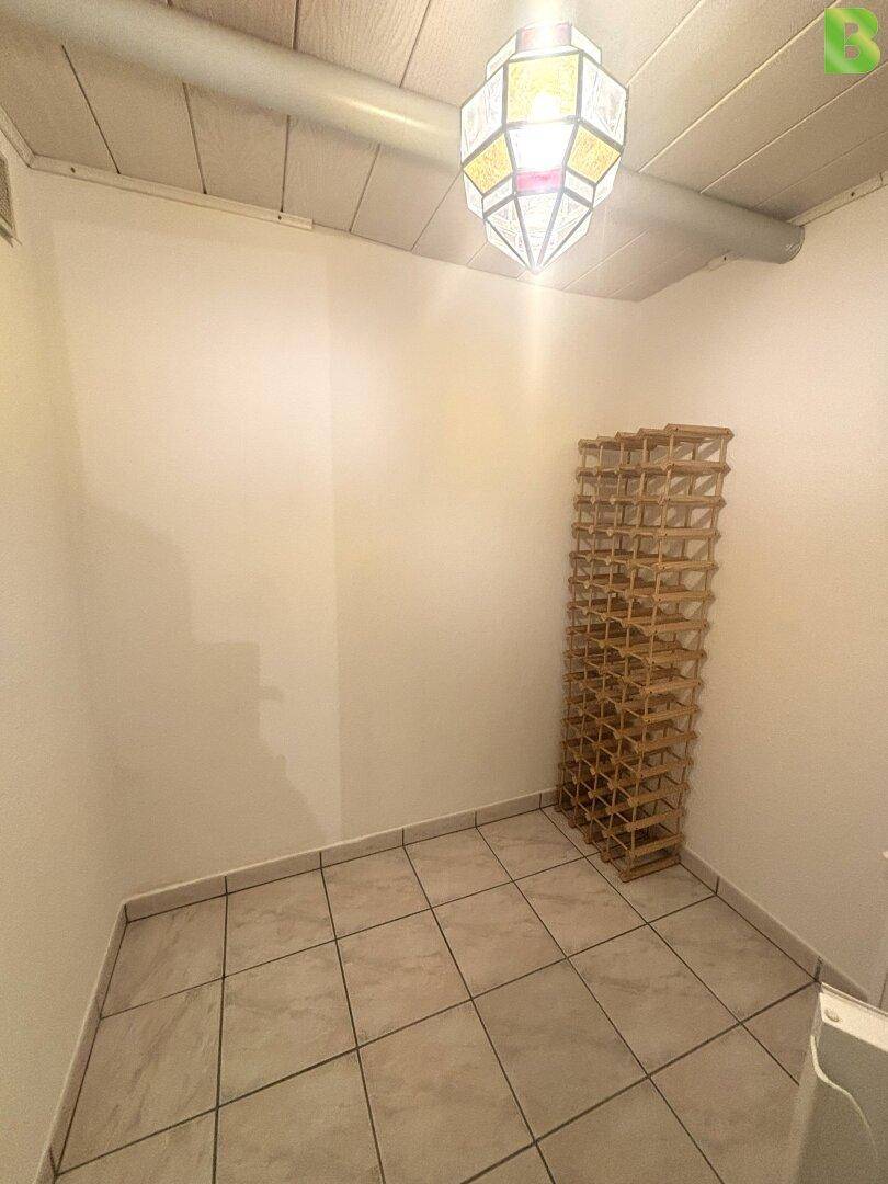 Kleiner Raum mit Holzregal für Flaschen und Fliesenboden, ideal als Weinkeller.