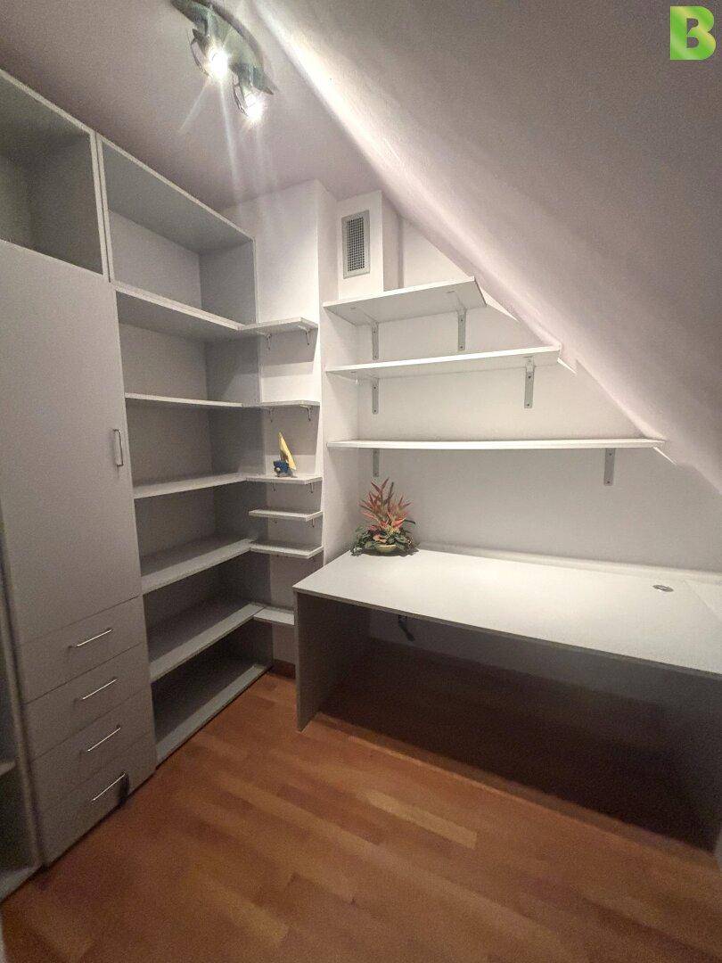 Dachgeschoss-Büro mit Schreibtisch, Regalen und schräger Decke, ideal für Home-Office.