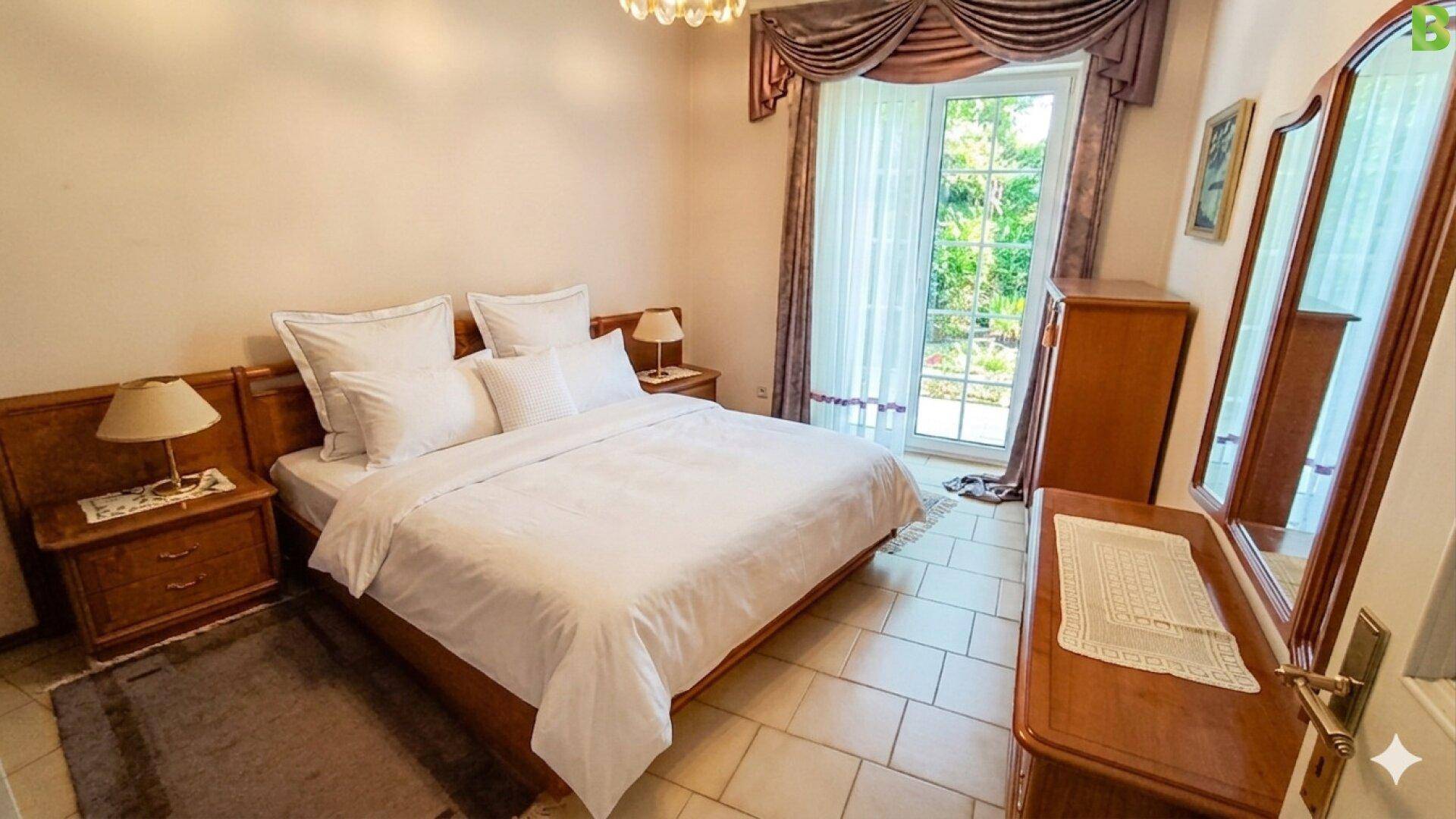 Schlafzimmer mit Doppelbett, Holzmöbeln und Zugang zum Garten.
