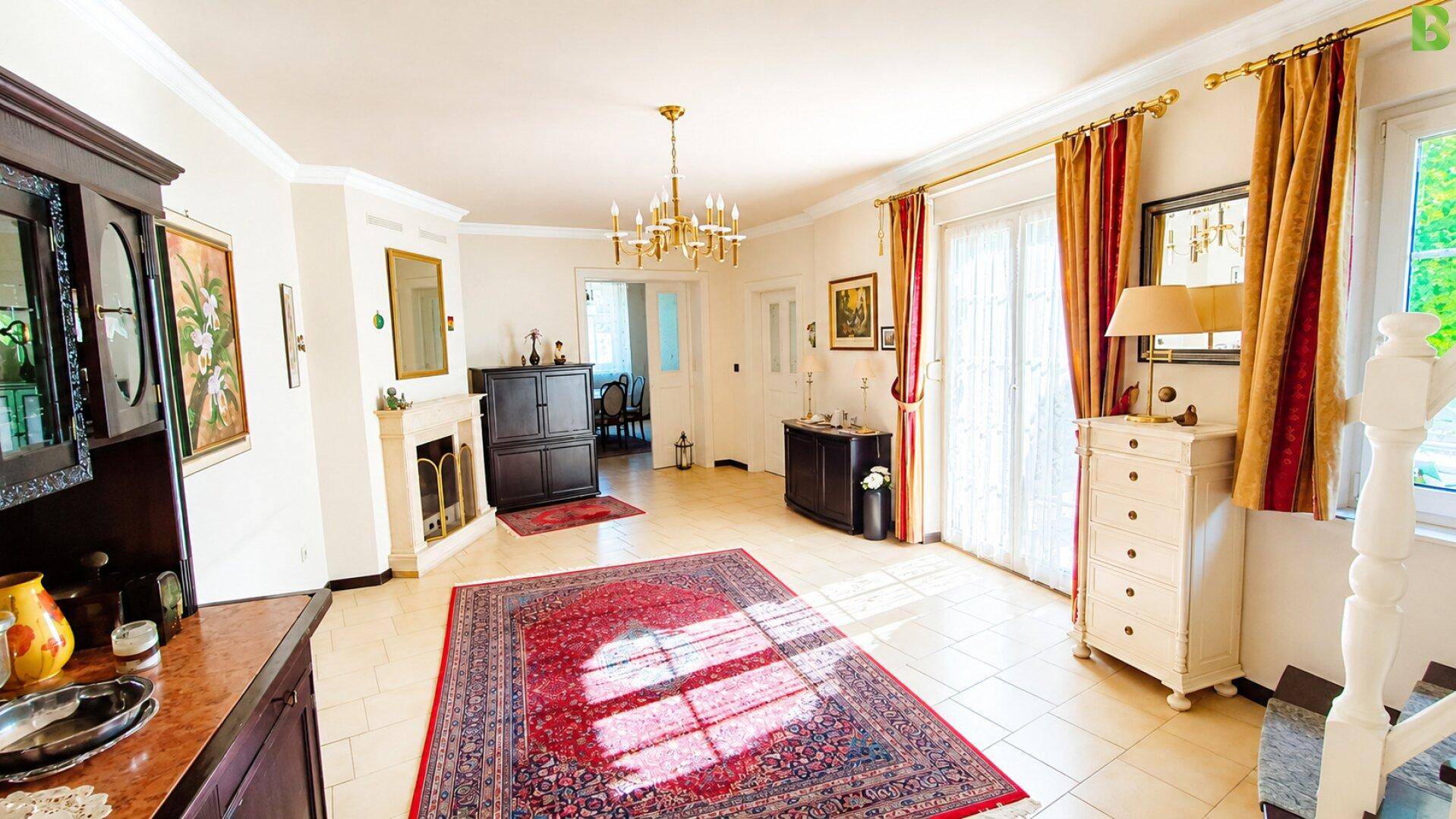 Geräumiges Wohnzimmer mit Kamin, Fliesenboden und Zugang zum Außenbereich.