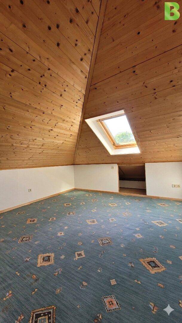 Dachgeschossraum mit Holzverkleidung an Decke und Schrägen sowie Dachfenster.