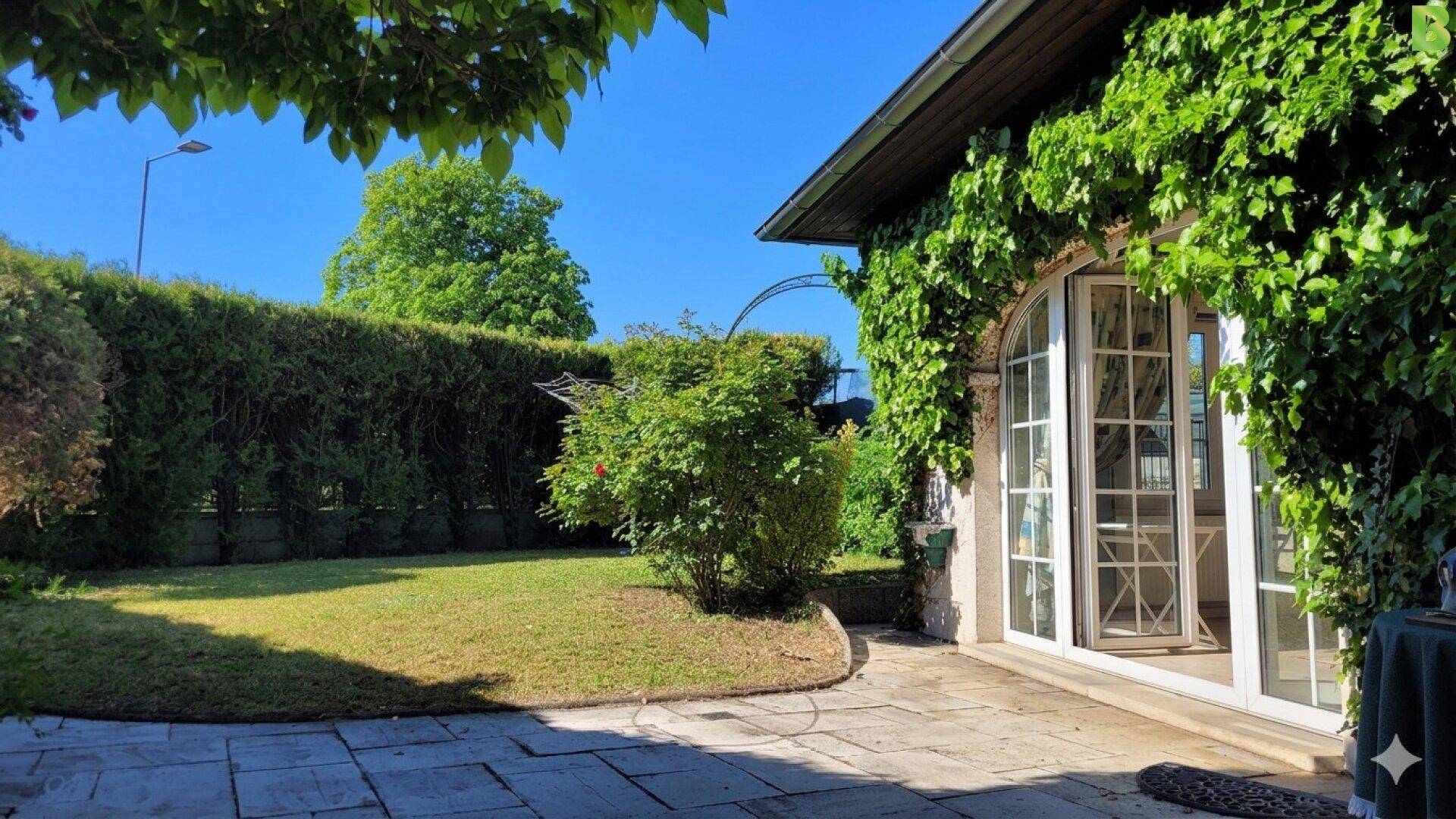 Gepflegter Garten mit Rasenfläche, Hecke und Zugang zur Terrasse.