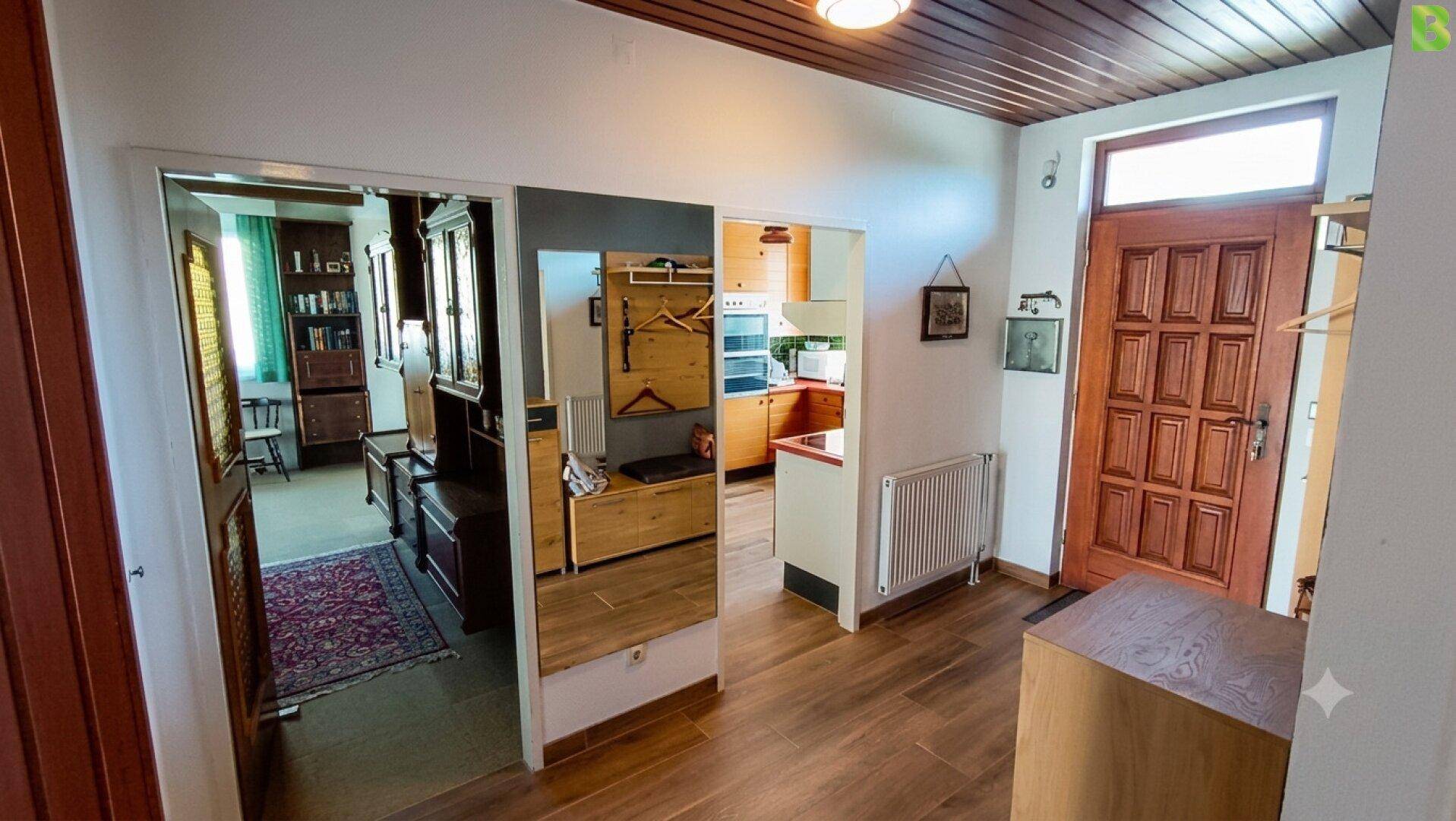Eingangsbereich mit Holztür, Spiegel und Blick in angrenzende Wohnbereiche.