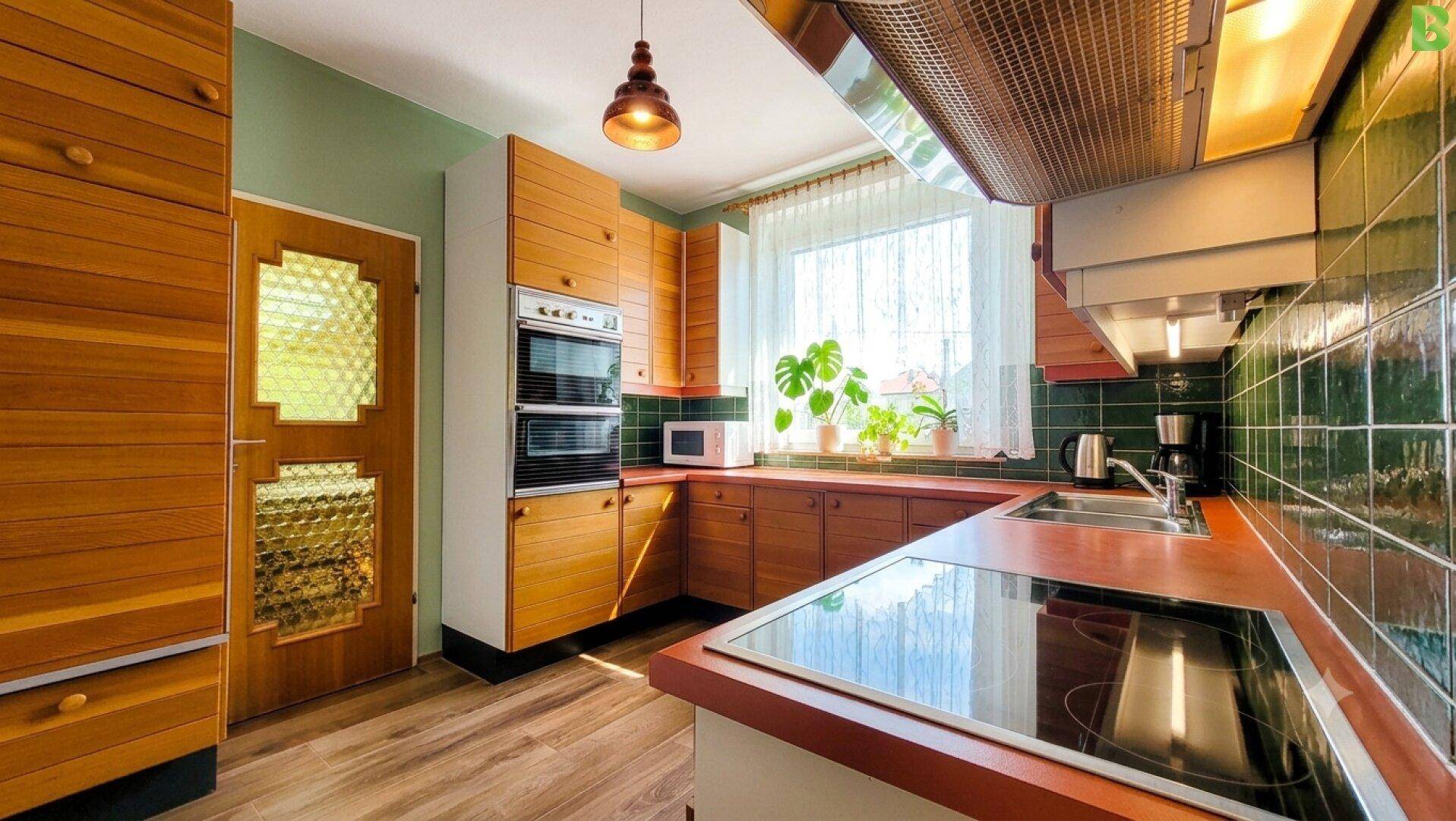 Traditionelle Küche mit Holzschränken, grünen Fliesen und Induktionskochfeld.