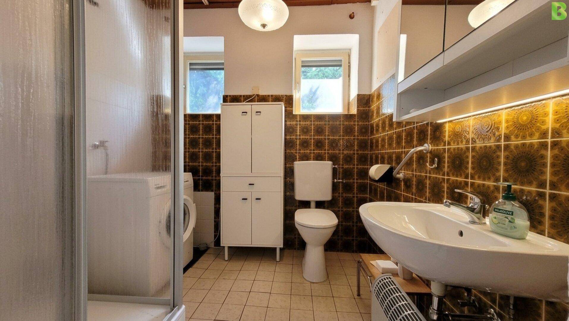 Badezimmer im 80er-Jahre-Stil mit Dusche, Waschbecken und braunen Fliesen.