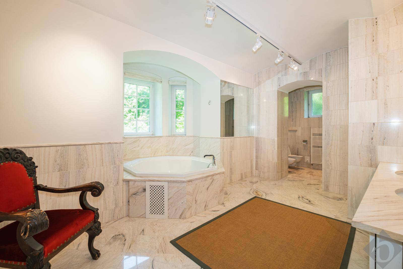 Geräumiges Badezimmer mit luxuriösen Marmorfliesen, einer Eckbadewanne und einem separaten WC-Bereich.