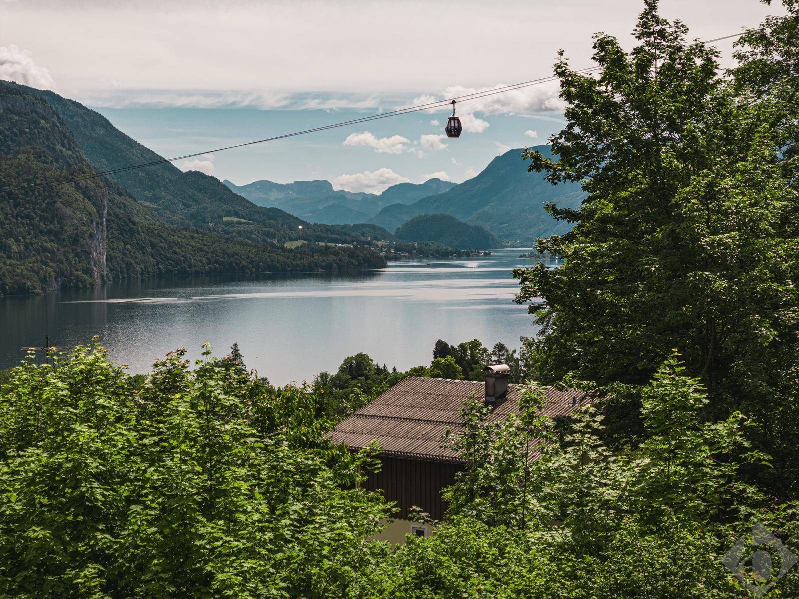 Idyllischer Blick auf einen Bergsee mit Seilbahn und umliegender alpiner Landschaft.