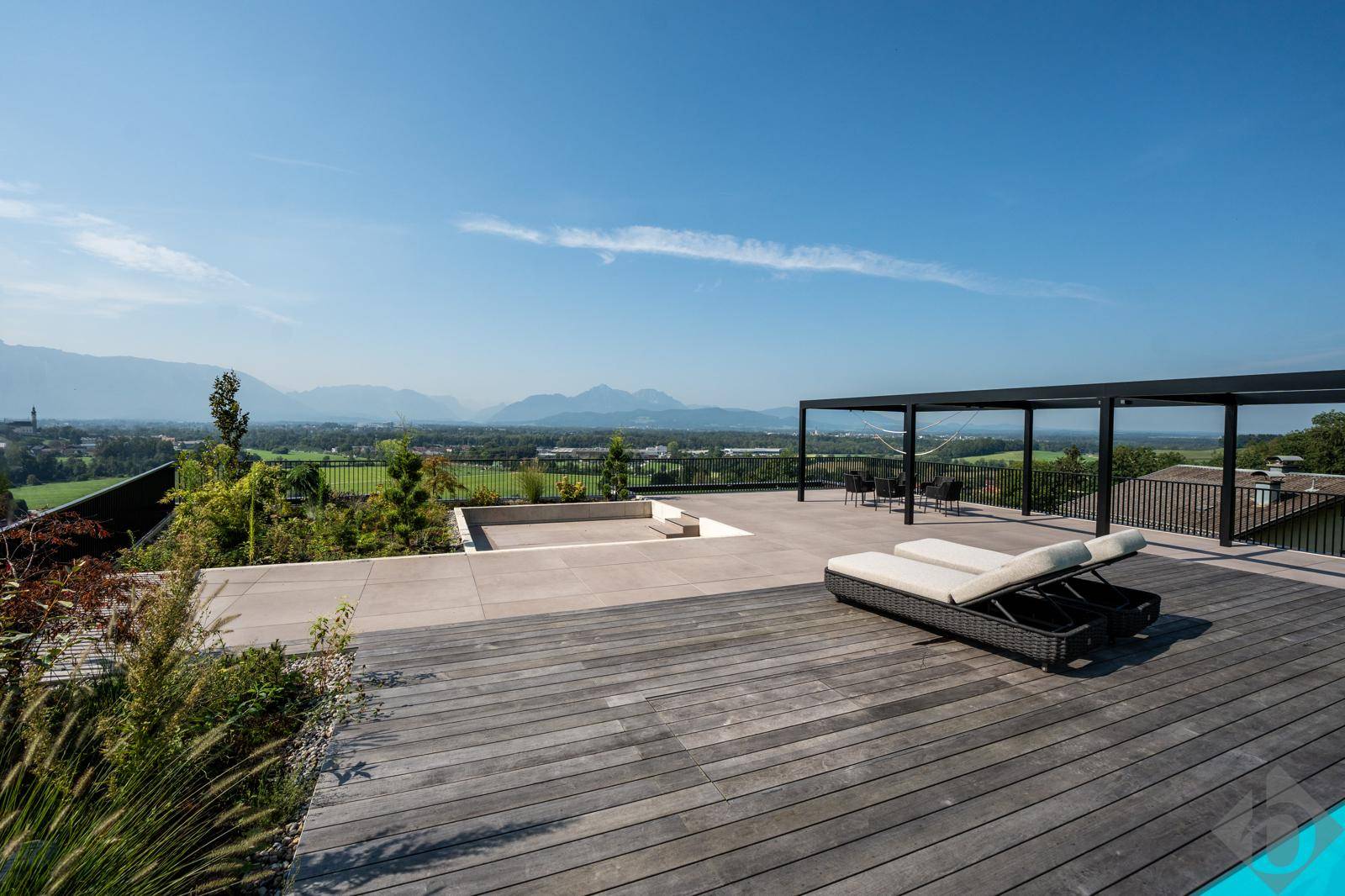 Exklusive Poolterrasse mit Liegestühlen, weitem Blick und moderner Gestaltung unter blauem Himmel.