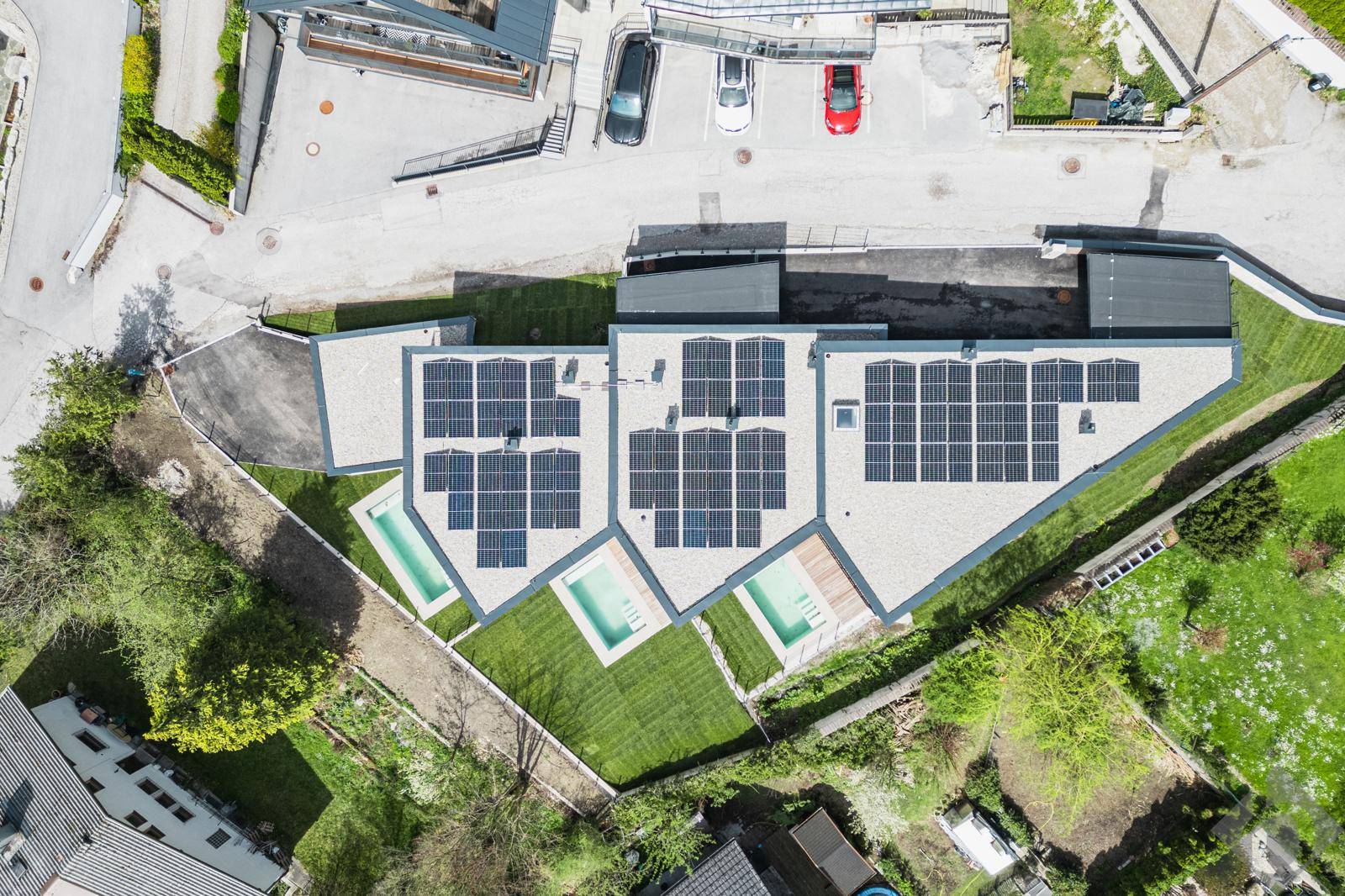 Luftaufnahme moderner Gebäude mit Solaranlagen auf den Dächern und privaten Pools.