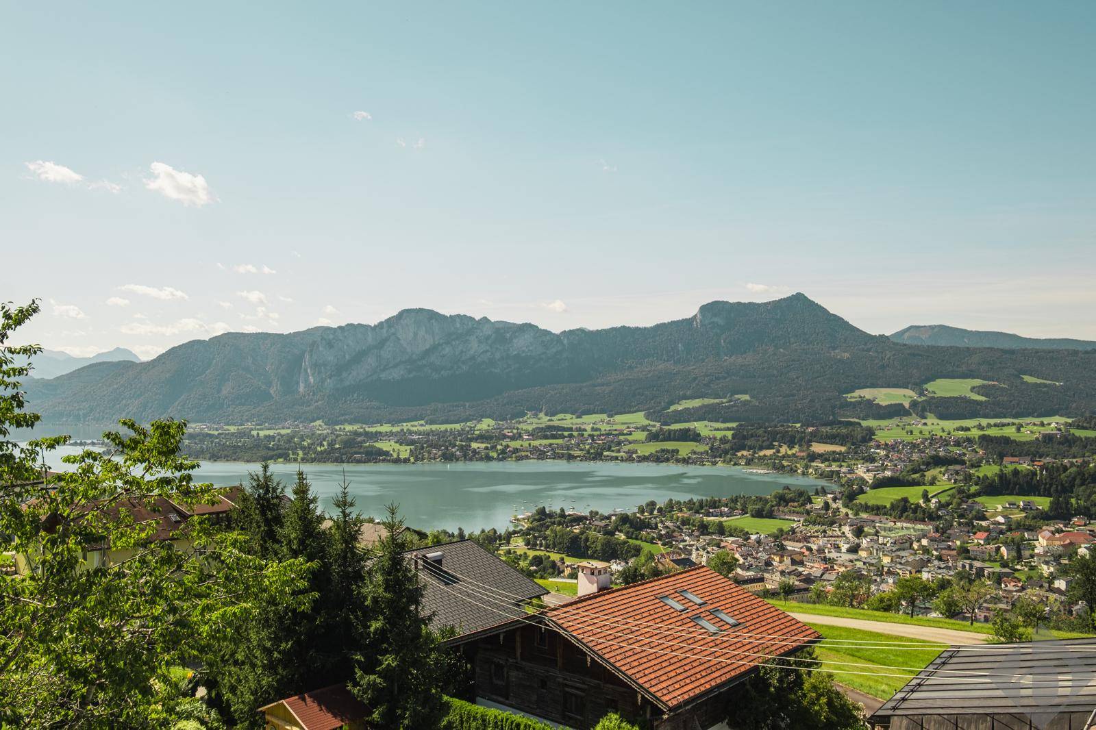 Malerischer Panoramablick über einen See, eine Stadt und die umliegende Berglandschaft.