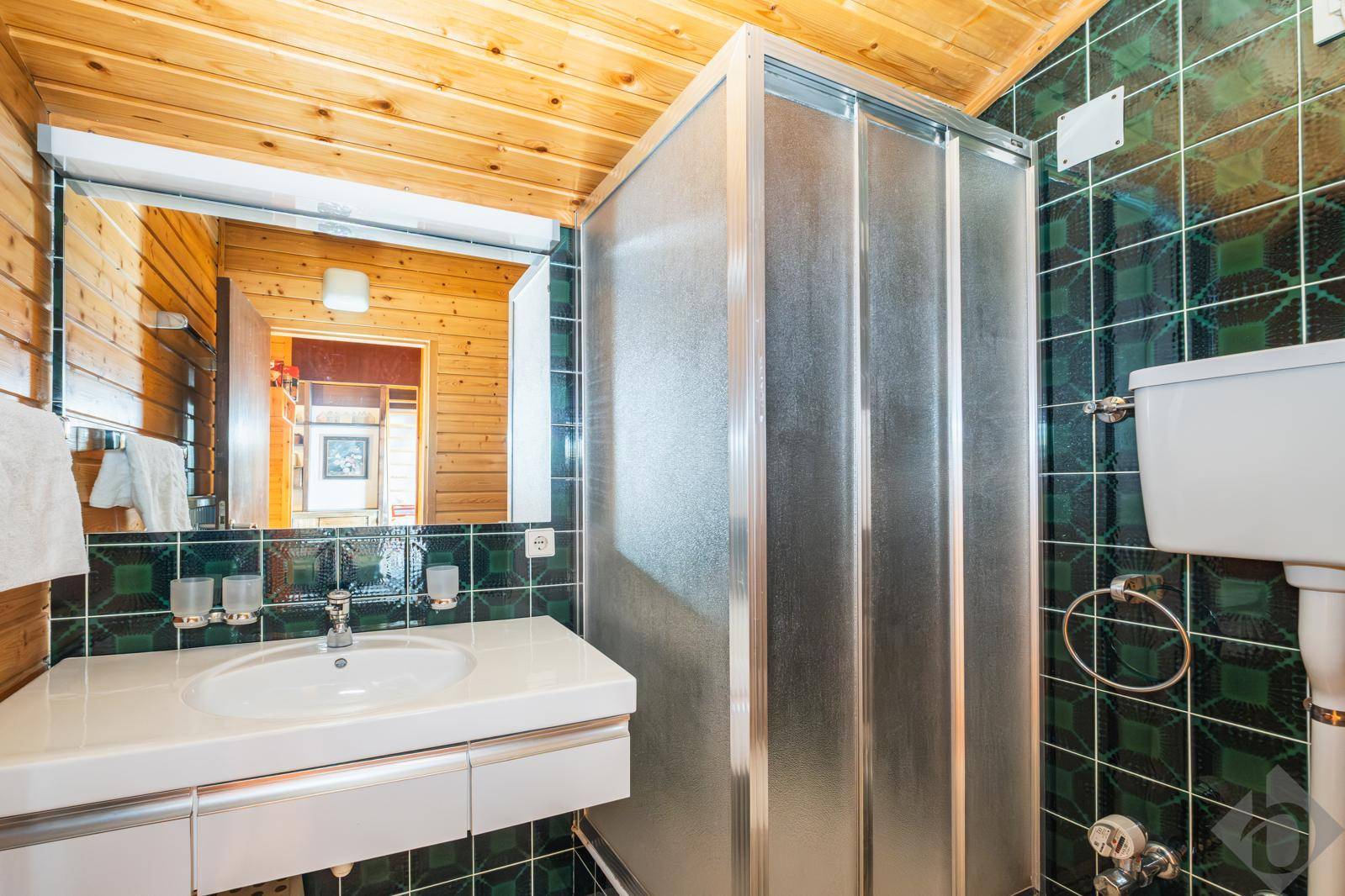 Badezimmer im Vintage-Stil mit grünen Kachelfliesen, Duschkabine und Holzdecke.