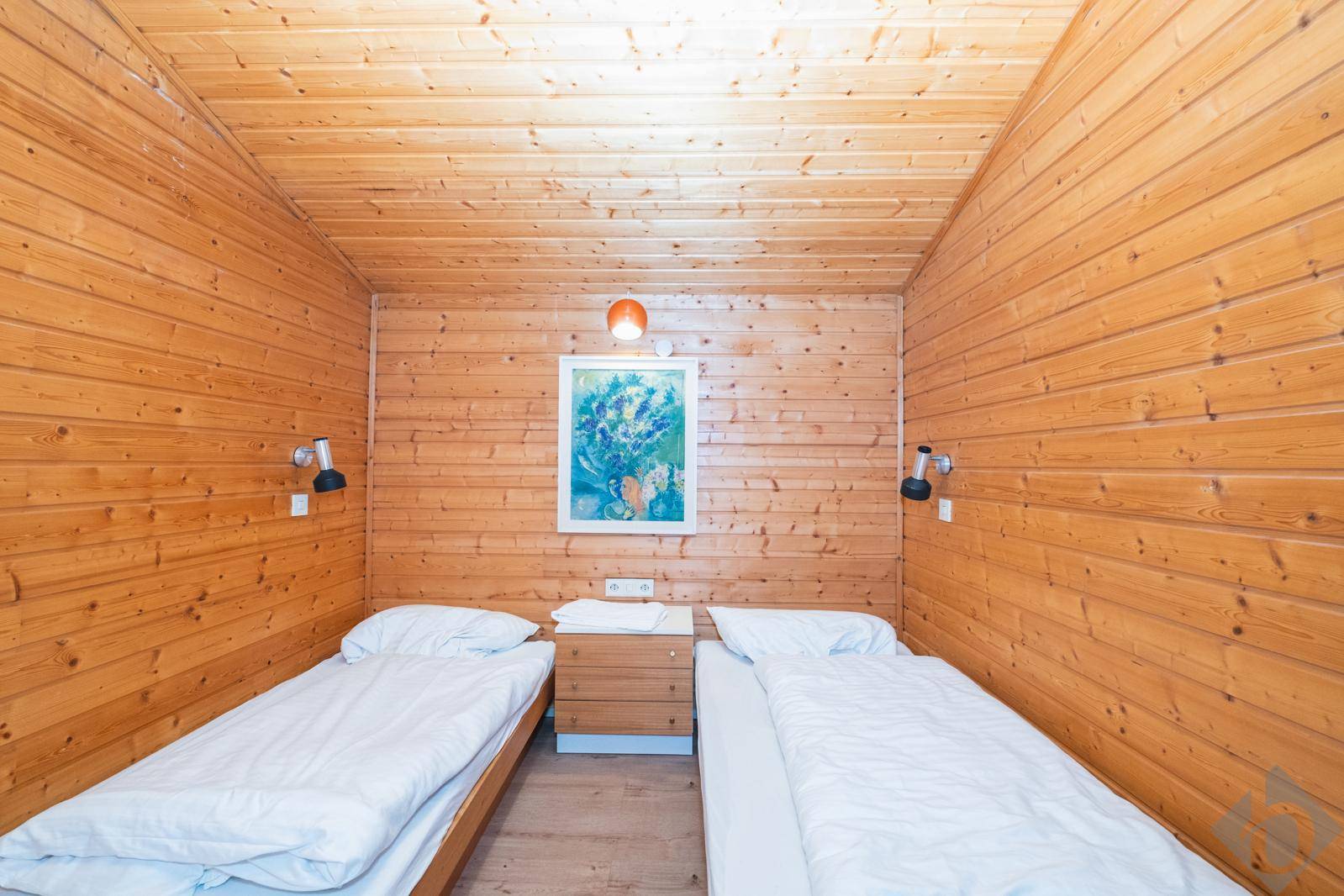 Gemütliches Schlafzimmer mit Holzvertäfelung, zwei Einzelbetten und einfacher Einrichtung.