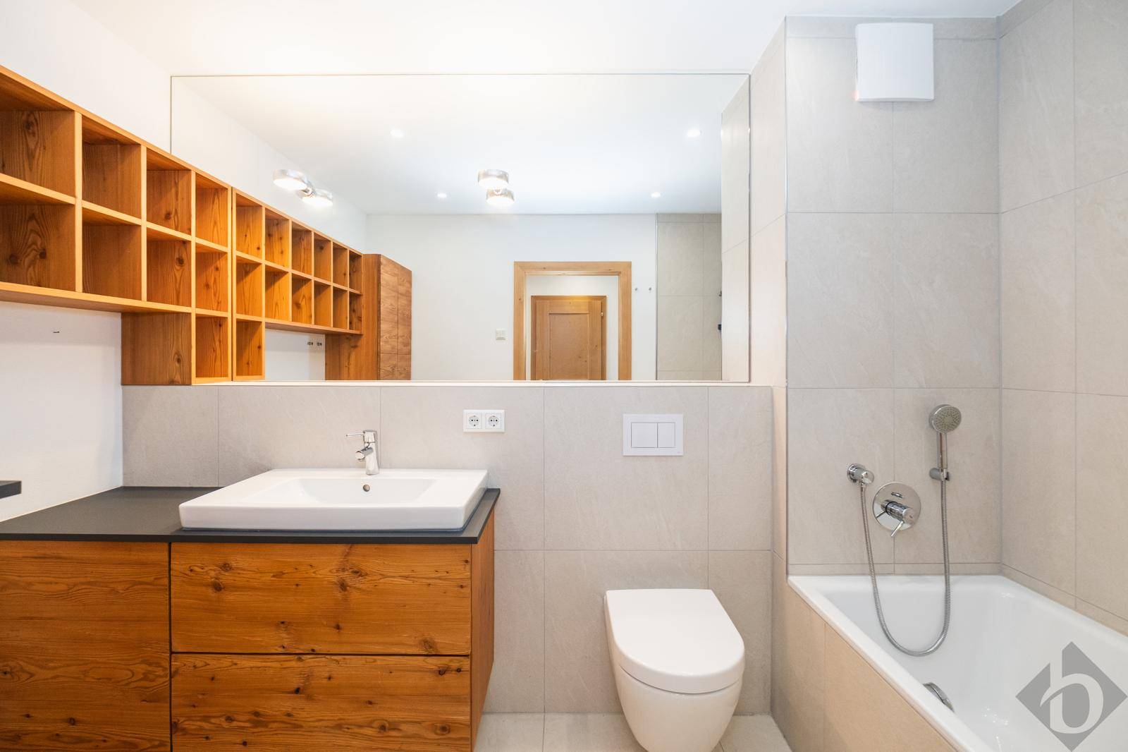 Modernes Badezimmer mit Badewanne, Einzelwaschbecken und praktischen Holzregalen.
