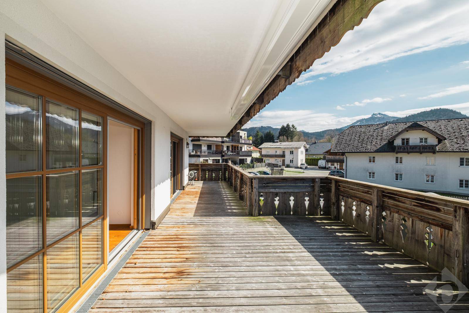 Geräumige Holzterrasse mit traditionellem Geländer und weitem Blick auf die umliegende Berglandschaft.