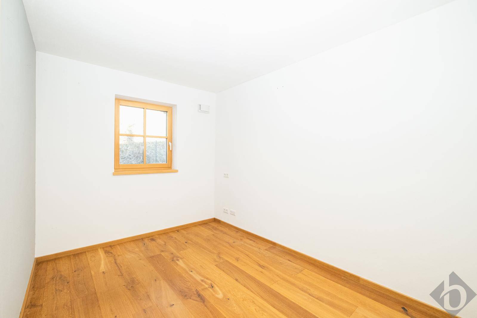 Heller, leerer Raum mit Holzboden und einem Fenster, vielseitig nutzbar.