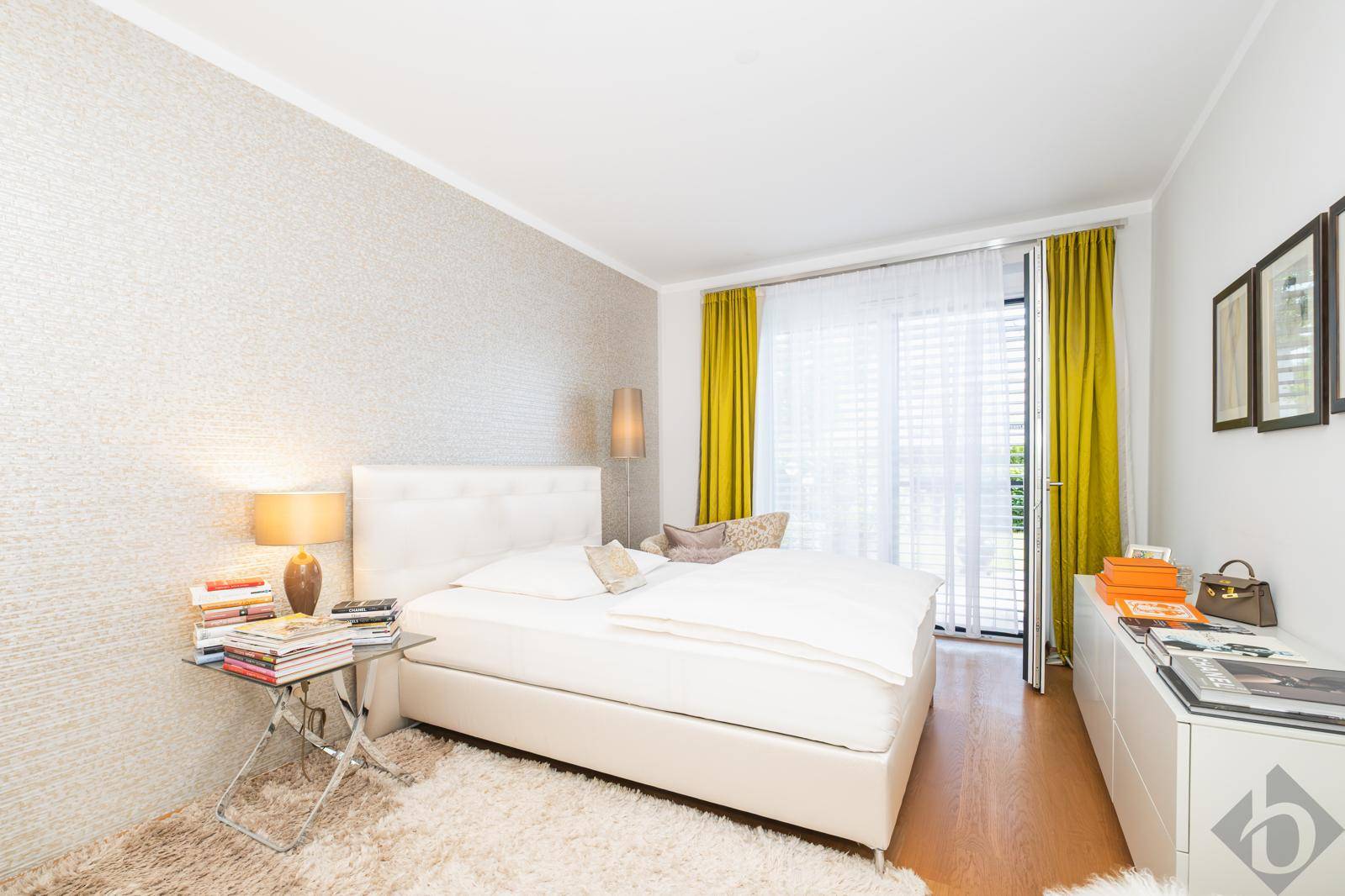 Helles Schlafzimmer mit Doppelbett, Parkettboden und Zugang zum Balkon.