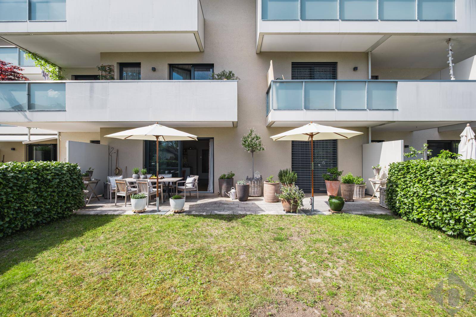 Moderne Wohnanlage mit Terrassen und Balkonen, umgeben von Grünflächen.