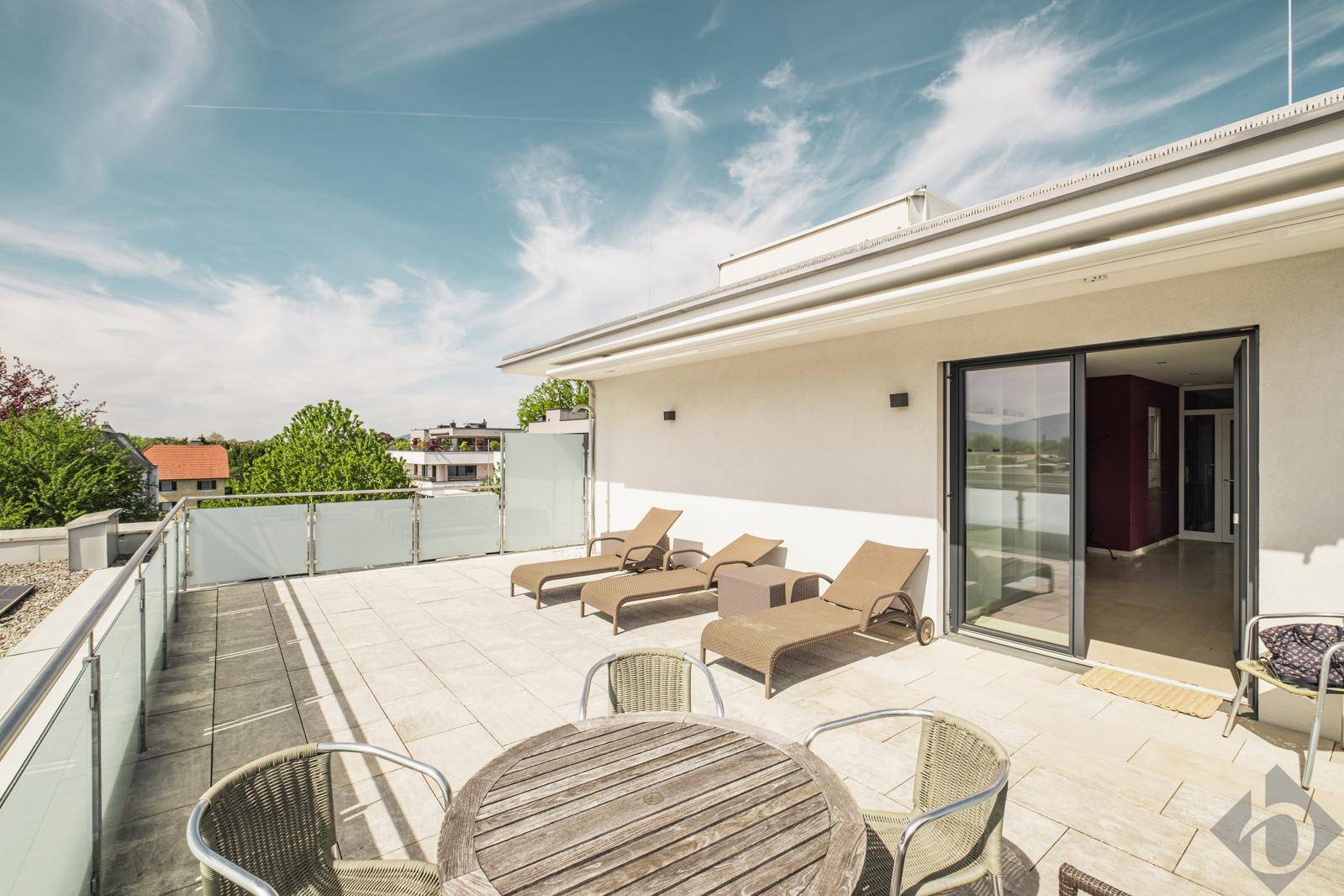 Weitläufige Dachterrasse mit Liegestühlen und Esstisch, ideal zum Entspannen.