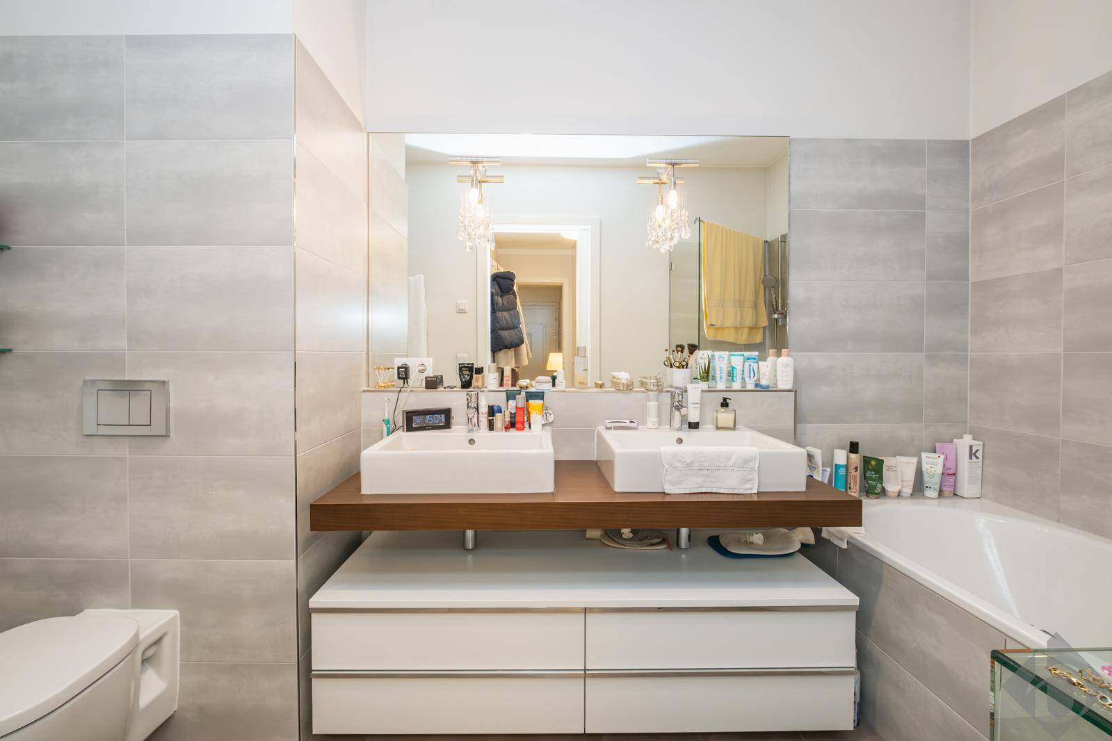 Modernes Badezimmer mit Doppelwaschbecken, Badewanne und großen grauen Fliesen.
