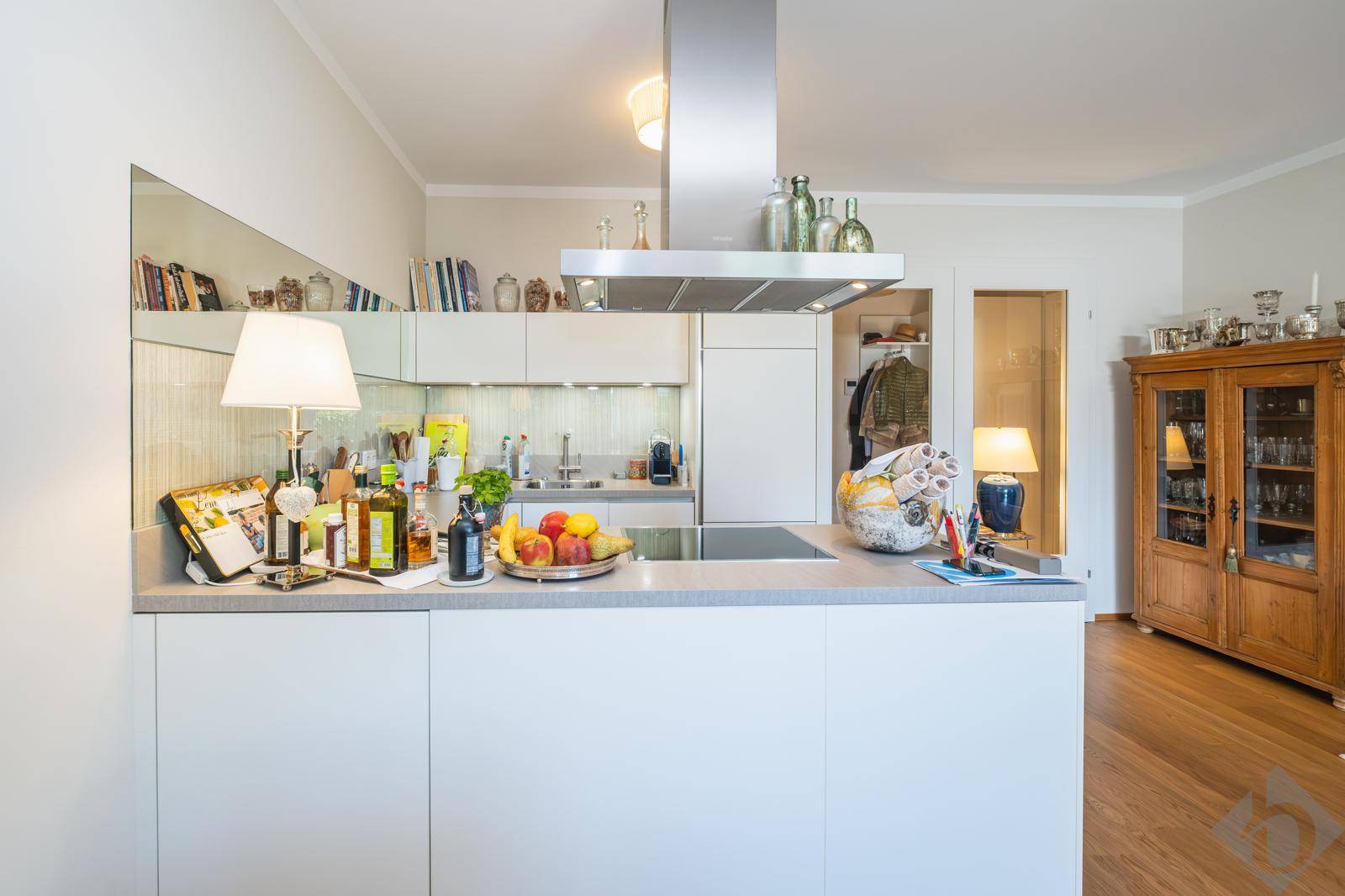 Moderne Küche mit Kochinsel, weißen Schränken und integrierten Geräten.