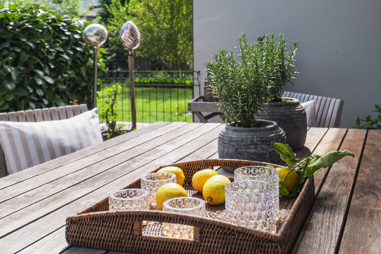 Detailansicht des Esstisches auf der Terrasse mit frischen Zitronen und Kräutern.
