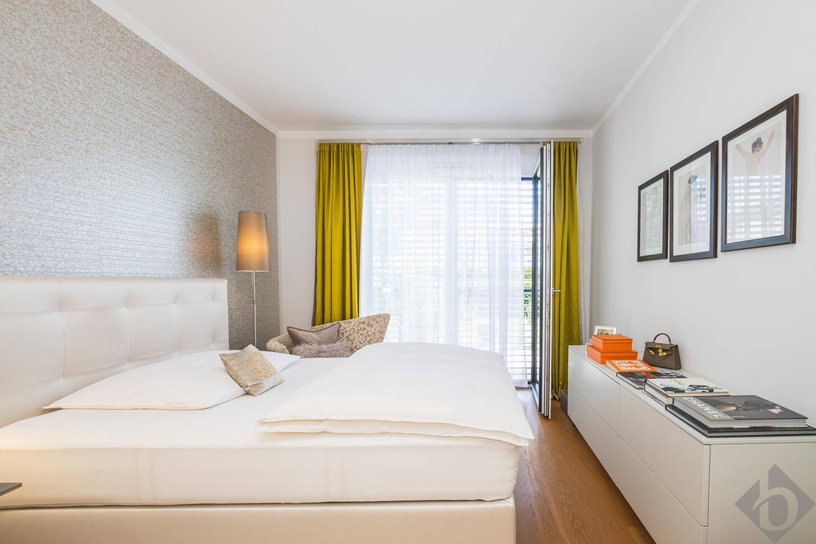 Modernes Schlafzimmer mit hellem Dekor, Parkettboden und Zugang zum Balkon.