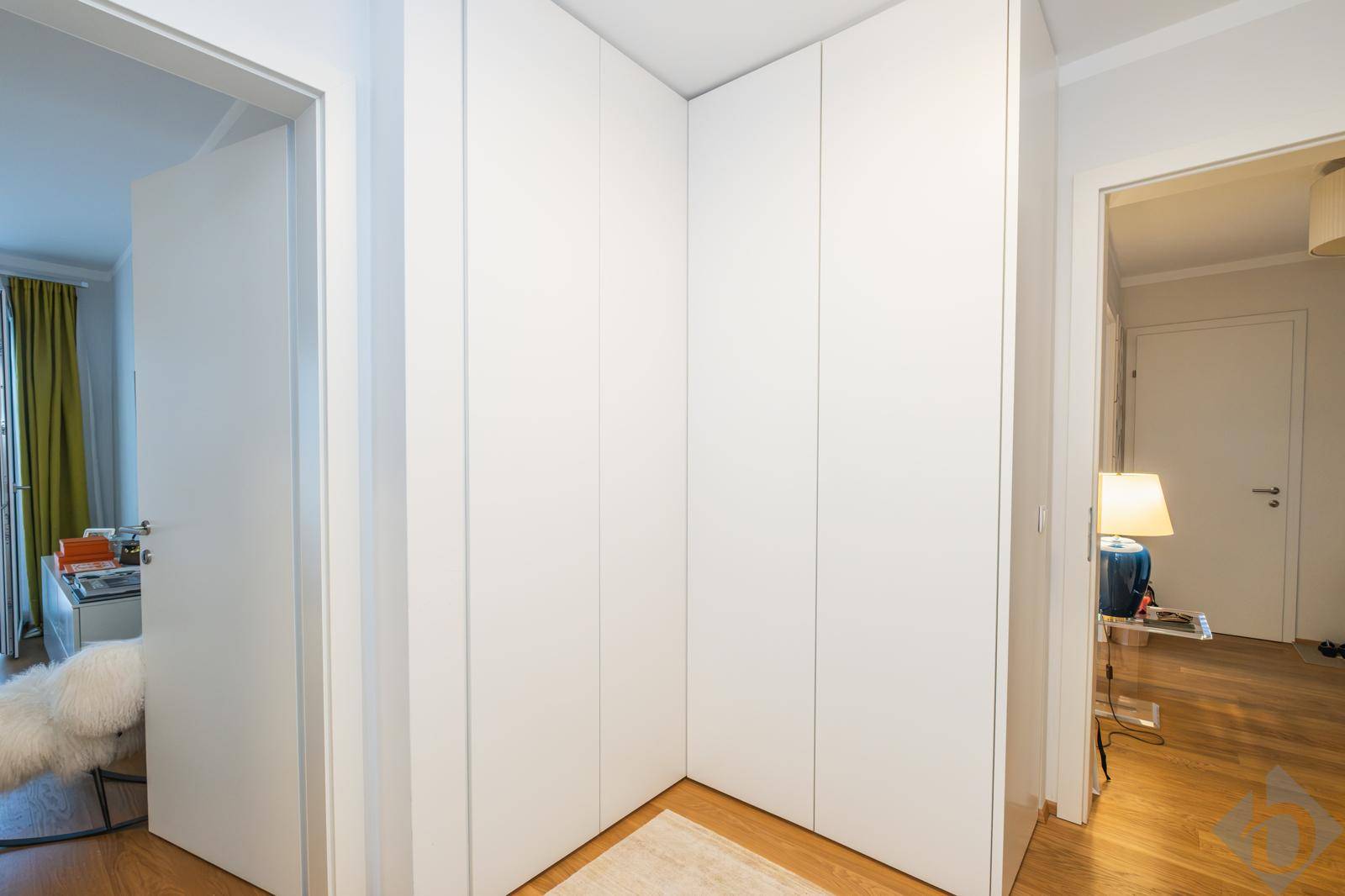 Heller Flur mit Einbauschränken und Holzboden, der zu den Zimmern führt.