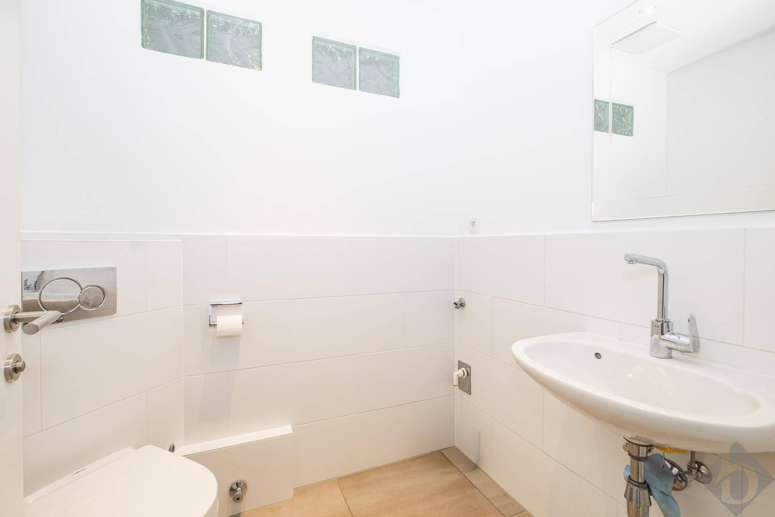 Modernes Gäste-WC mit wandhängendem WC, Waschbecken und Fliesenboden.