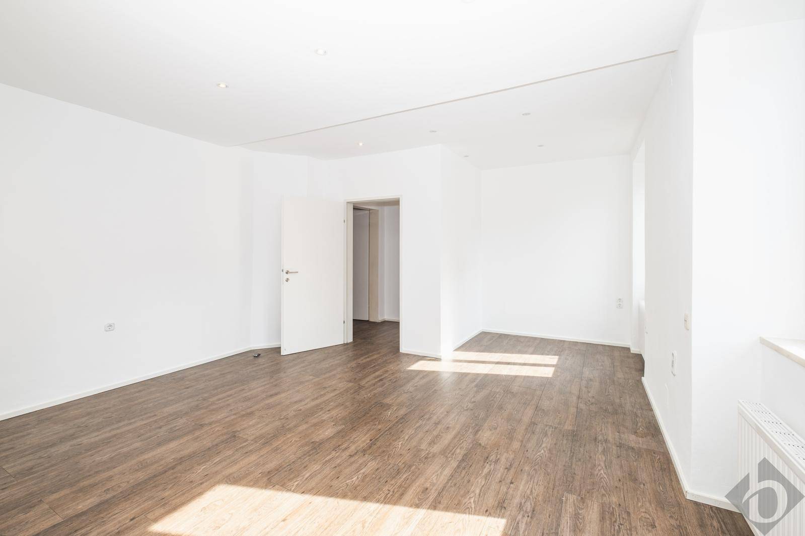 Geräumiger, heller Raum mit Laminatboden und viel Tageslicht, ideal für flexible Nutzung.
