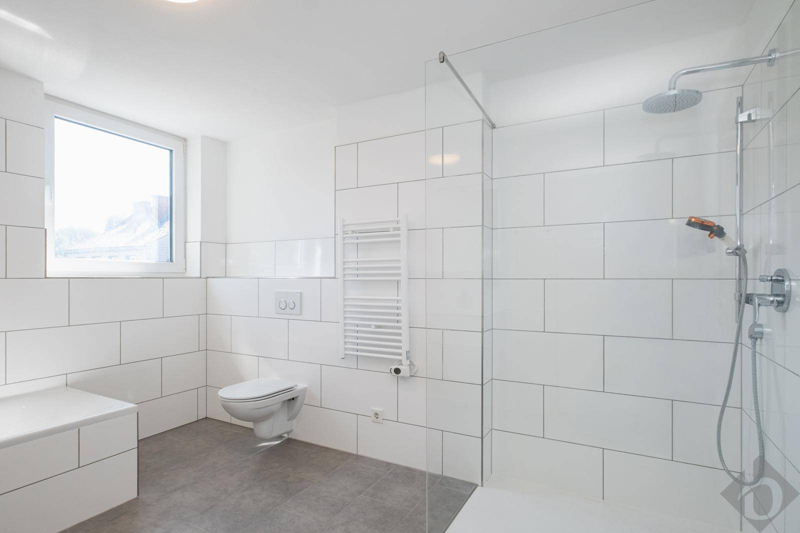 Modernes Badezimmer mit großer begehbarer Dusche, Wand-WC und Handtuchheizkörper.